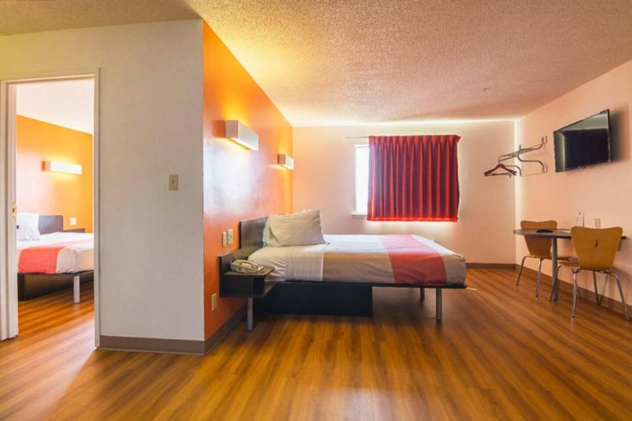 Quarto de hotel com cama, escrivaninha e televisão.
