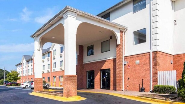A multi-story hotel with a covered entrance and a parking lot. - Spacious King Bed|Free Wifi,Parking (Jonesboro)