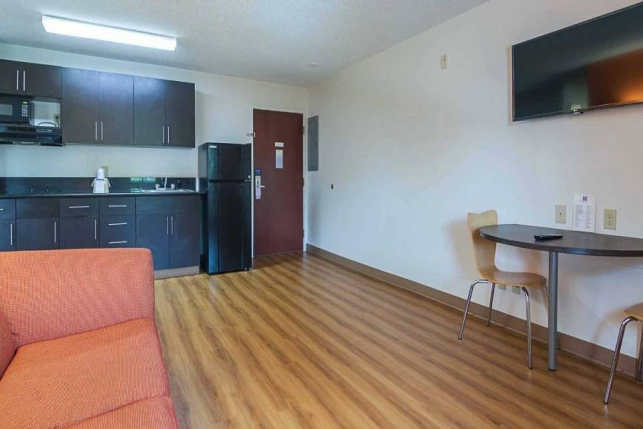 A compact living space with a kitchenette, a dining area with a table and chairs, and a sofa.