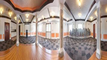 A spacious hall with a checkered floor, wooden flooring, and a seating arrangement.