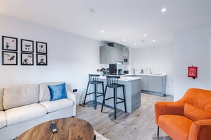 A modern living room with a sofa, a coffee table, and a kitchen area with a bar. - Stylish and Cosy 1 BDR Apt in Liverpool (Liverpool)