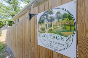 A wooden fence with a sign advertising 'The Cottage at Fairy Time Retreat.'