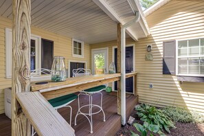 A wooden deck with a table and chairs, a window, and a door.