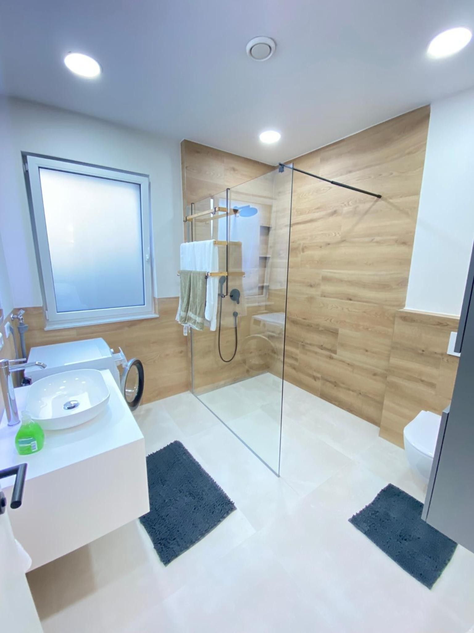 A modern bathroom with a glass shower enclosure, a white sink, and a mirror.