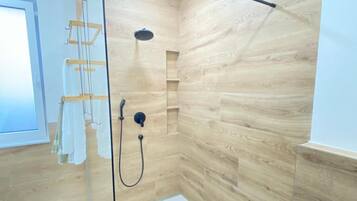 Ein modernes Badezimmer mit einer gläsernen Duschkabine, Holzpaneelen an den Wänden und einem Fenster.