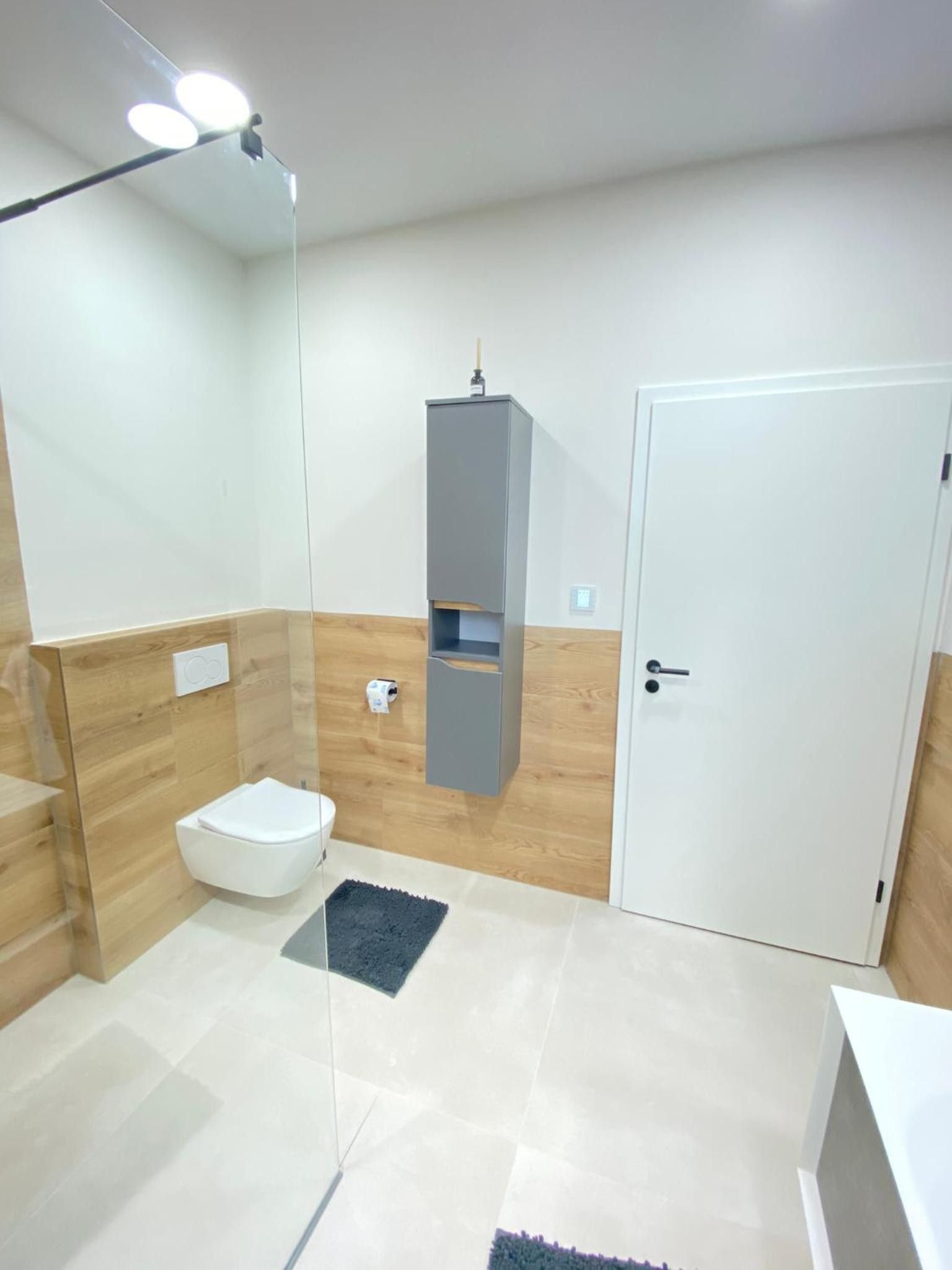 Un baño moderno con cabina de ducha de vidrio, inodoro, lavamanos y puerta.