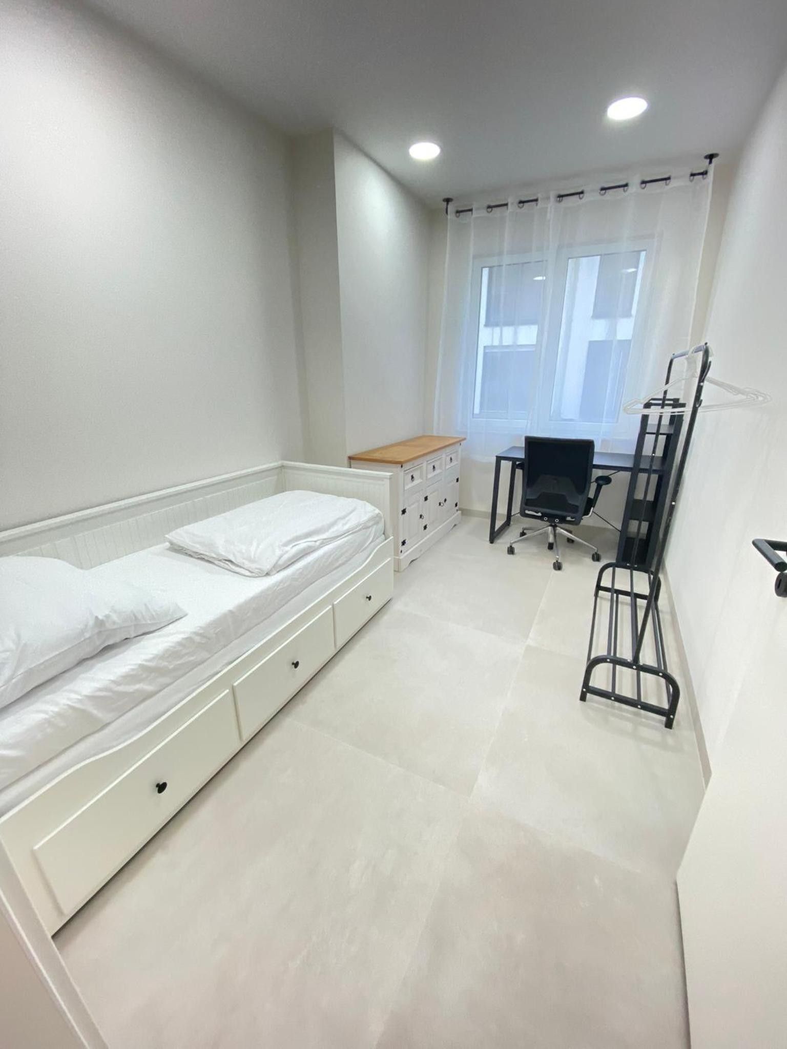 Een slaapkamer met een enkel bed, een bureau en een stoel.