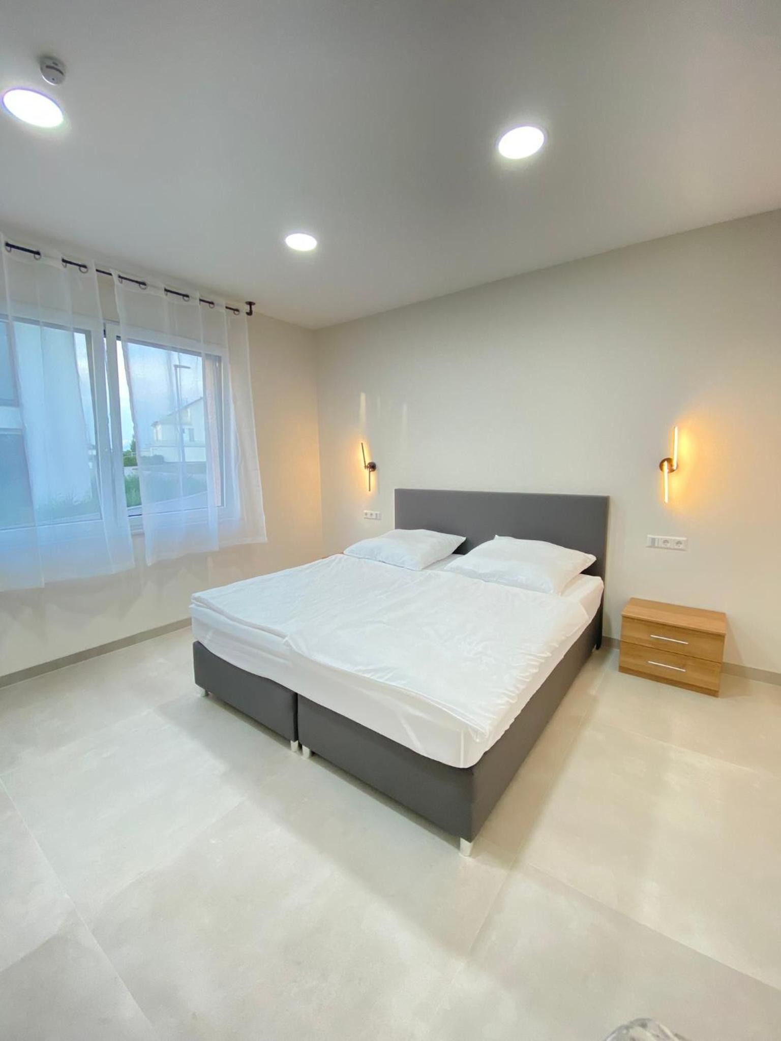 A modern bedroom with a large bed, bedside tables, and a window with curtains.