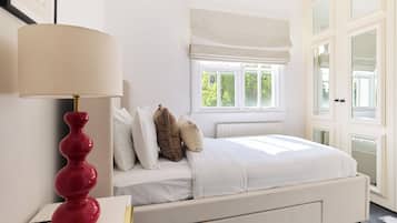 A bedroom with a bed, a nightstand, a lamp, a window, and a door.