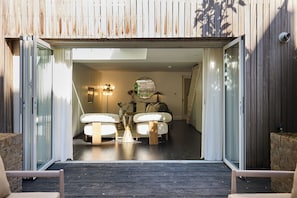 A modern interior with a wooden exterior, a glass door entrance, a sofa, a coffee table, and a decorative mirror. - Notting Hill Floor by Floor (London)