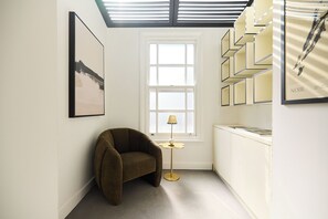 A room with a window, a chair, a lamp, and a shelf with items. - Notting Hill Floor by Floor (London)