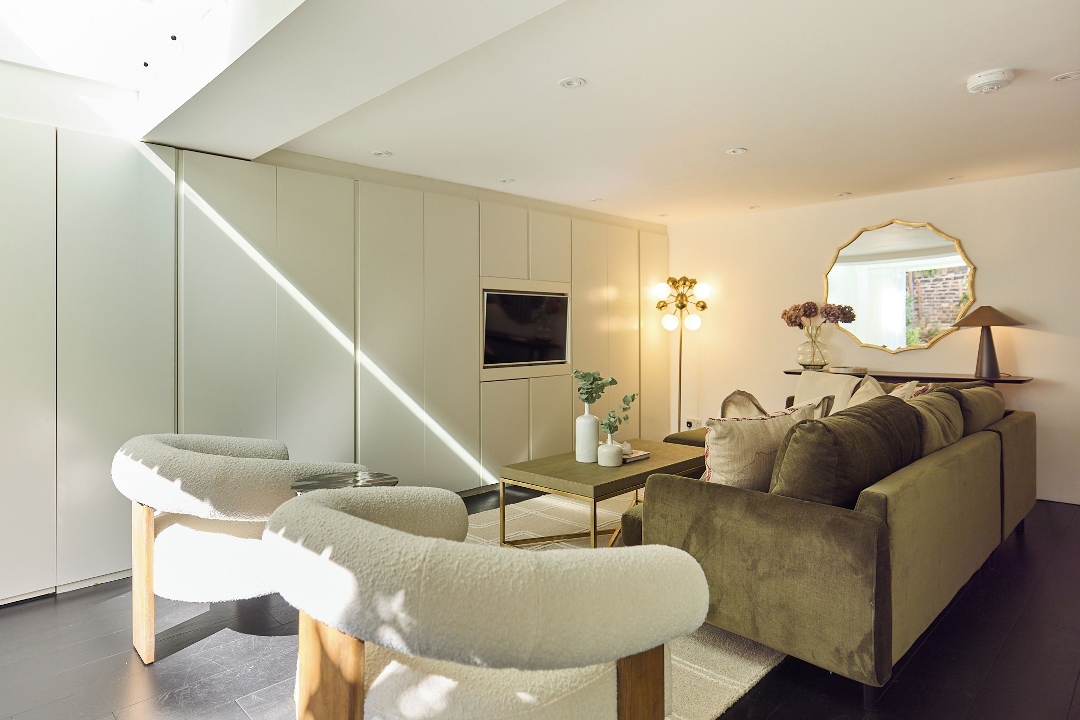 A modern living room with a sofa, a coffee table, and a TV mounted on the wall.