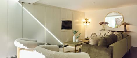 A modern living room with a sofa, a coffee table, and a TV mounted on the wall.