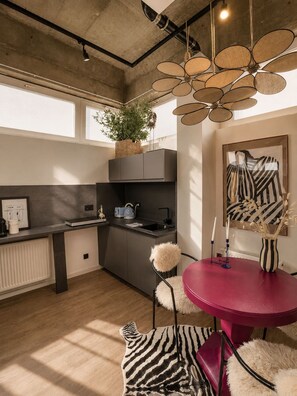 Eine moderne Küche mit Essbereich, ausgestattet mit einem außergewöhnlichen Deckenventilator, einer Topfpflanze und einem Zebra-Teppich.
