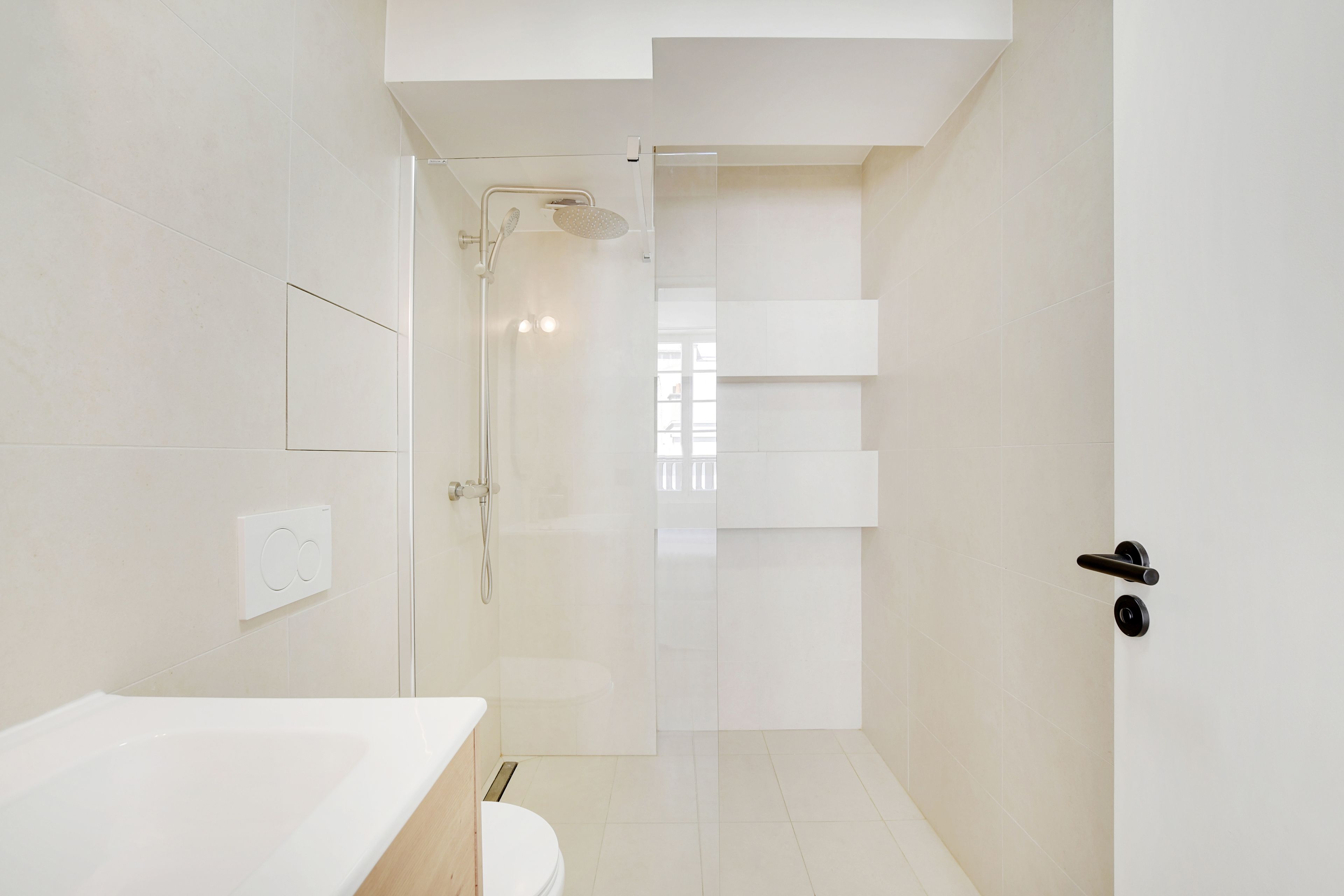 Un baño moderno con cabina de ducha de vidrio, una bañera blanca y un inodoro.