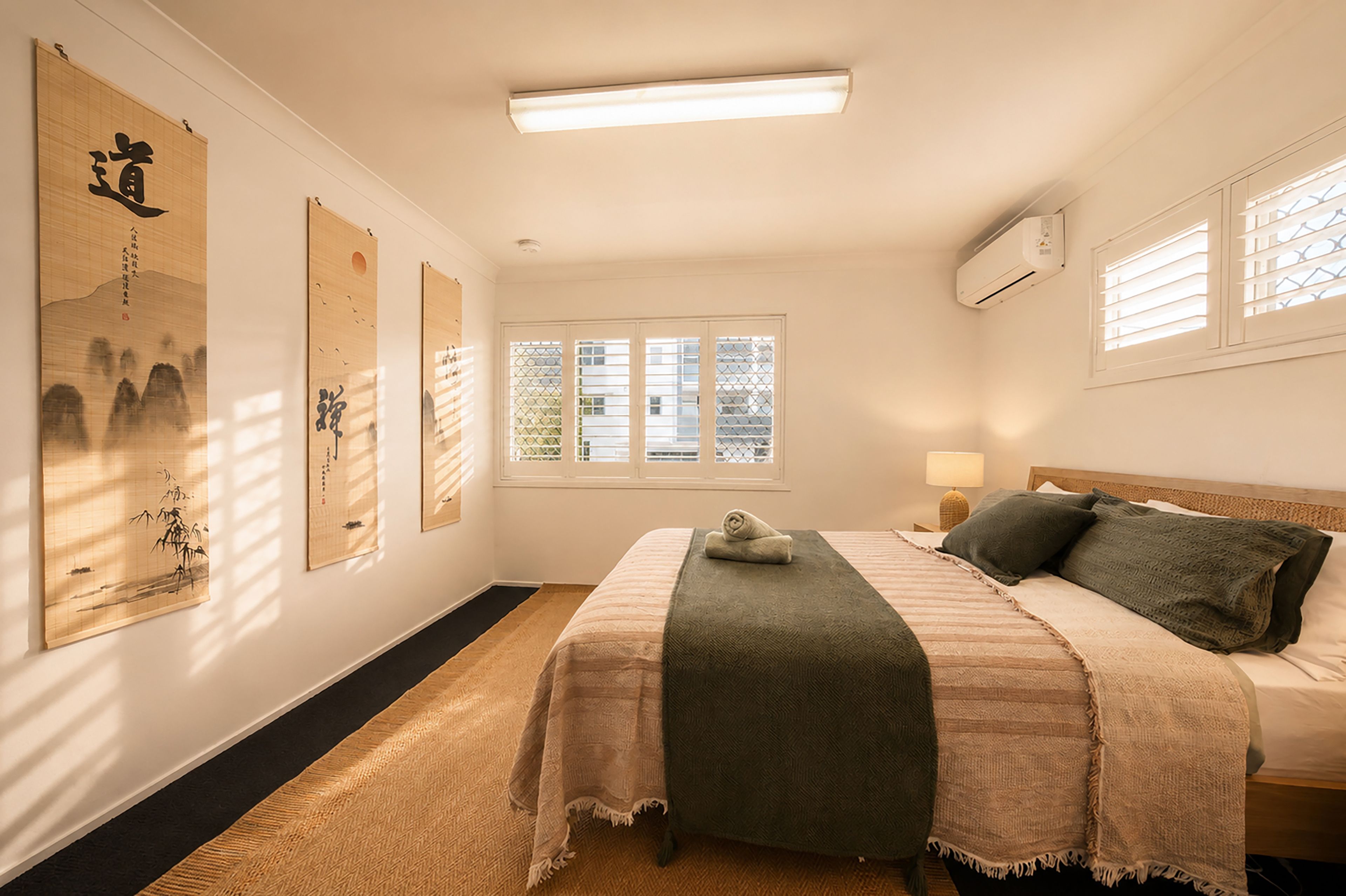 A bedroom with a bed, a window, and wall decorations.