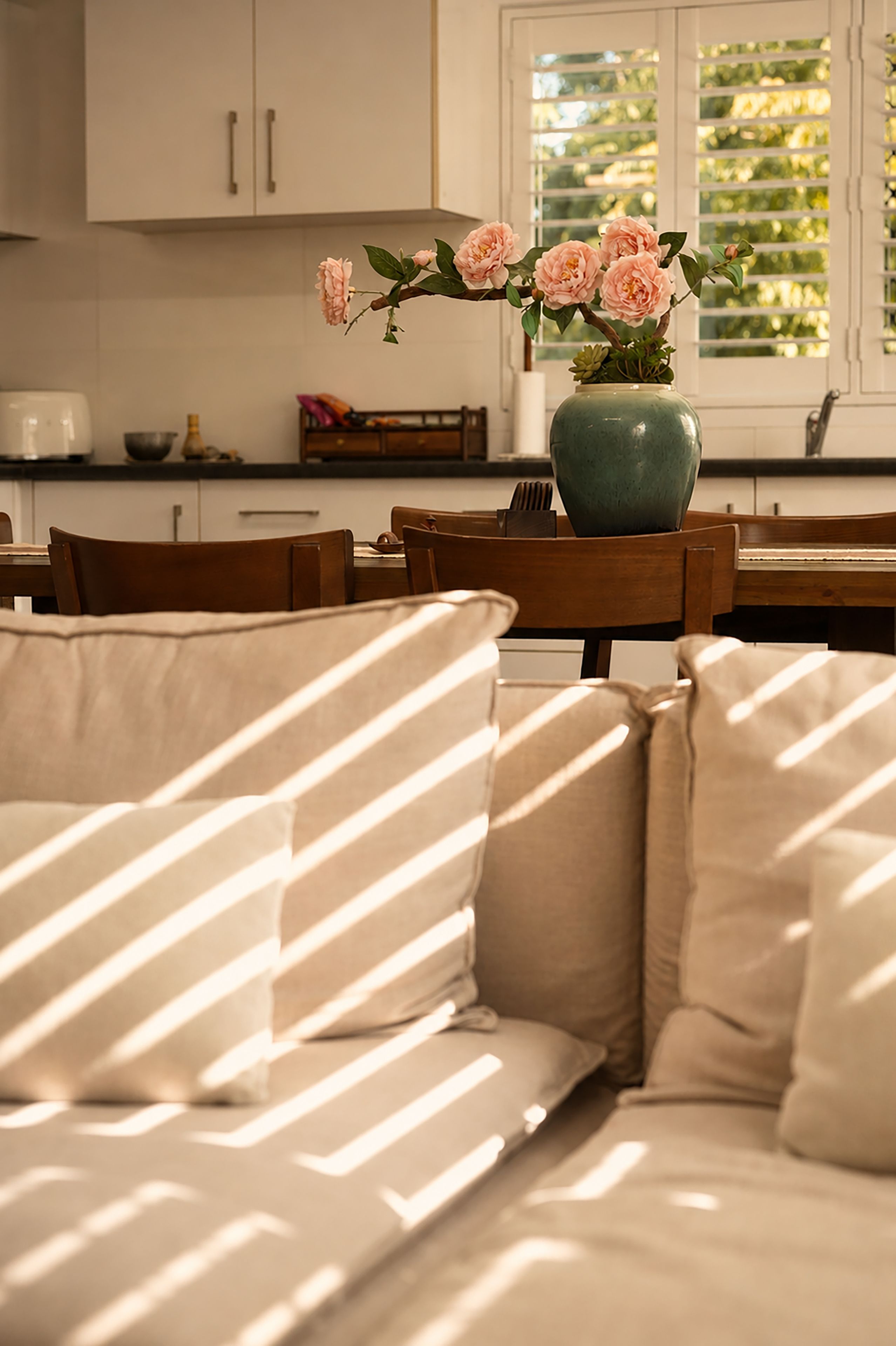 A cozy living room with a sofa, a table, and a vase with flowers.