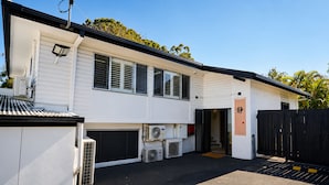 A two-story building with a garage, outdoor air conditioning units, and a black fence. - Zen Retreat: Cinema, Pet-Friendly Yard (Springwood)