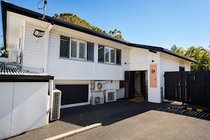 A two-story building with a garage, outdoor air conditioning units, and a black fence. - Zen Retreat: Cinema, Pet-Friendly Yard (Springwood)