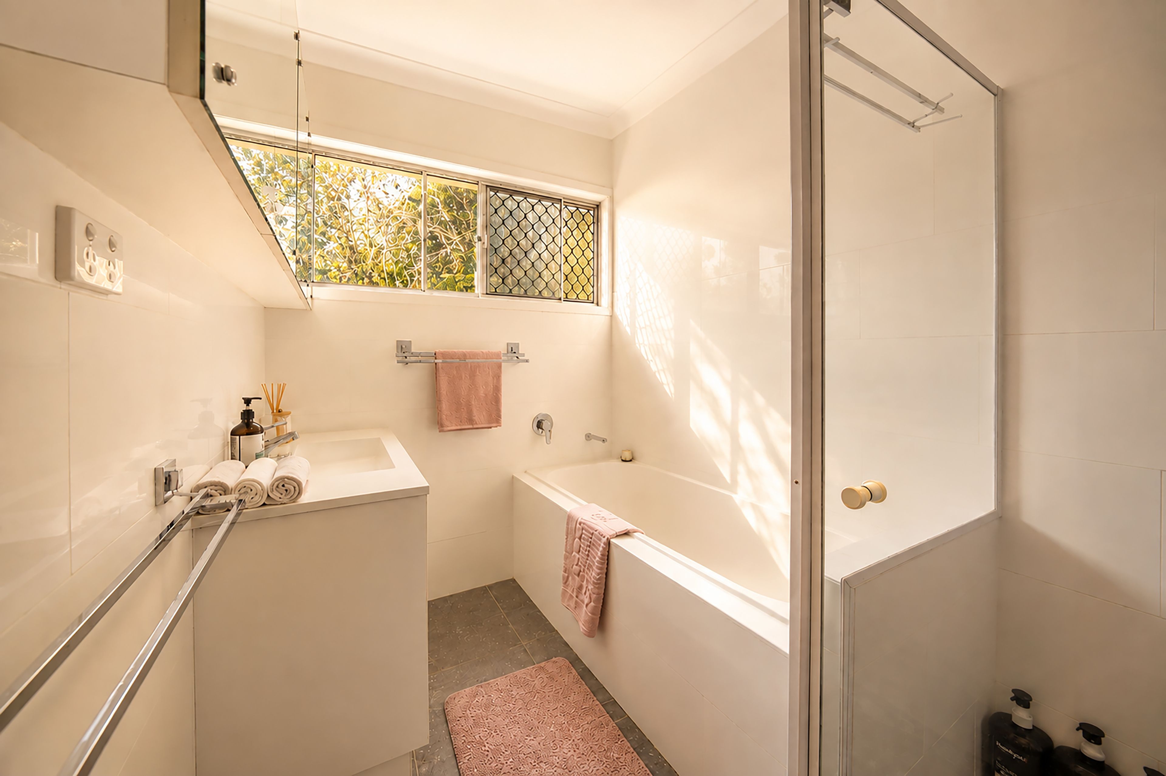A modern bathroom with a shower, a bathtub, and a window.