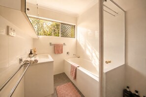 A modern bathroom with a shower, a bathtub, and a window. - Zen Retreat: Cinema, Pet-Friendly Yard (Springwood)