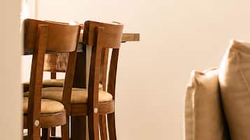 A dining area with wooden chairs and a table, a beige rug, and a wall-mounted painting.
