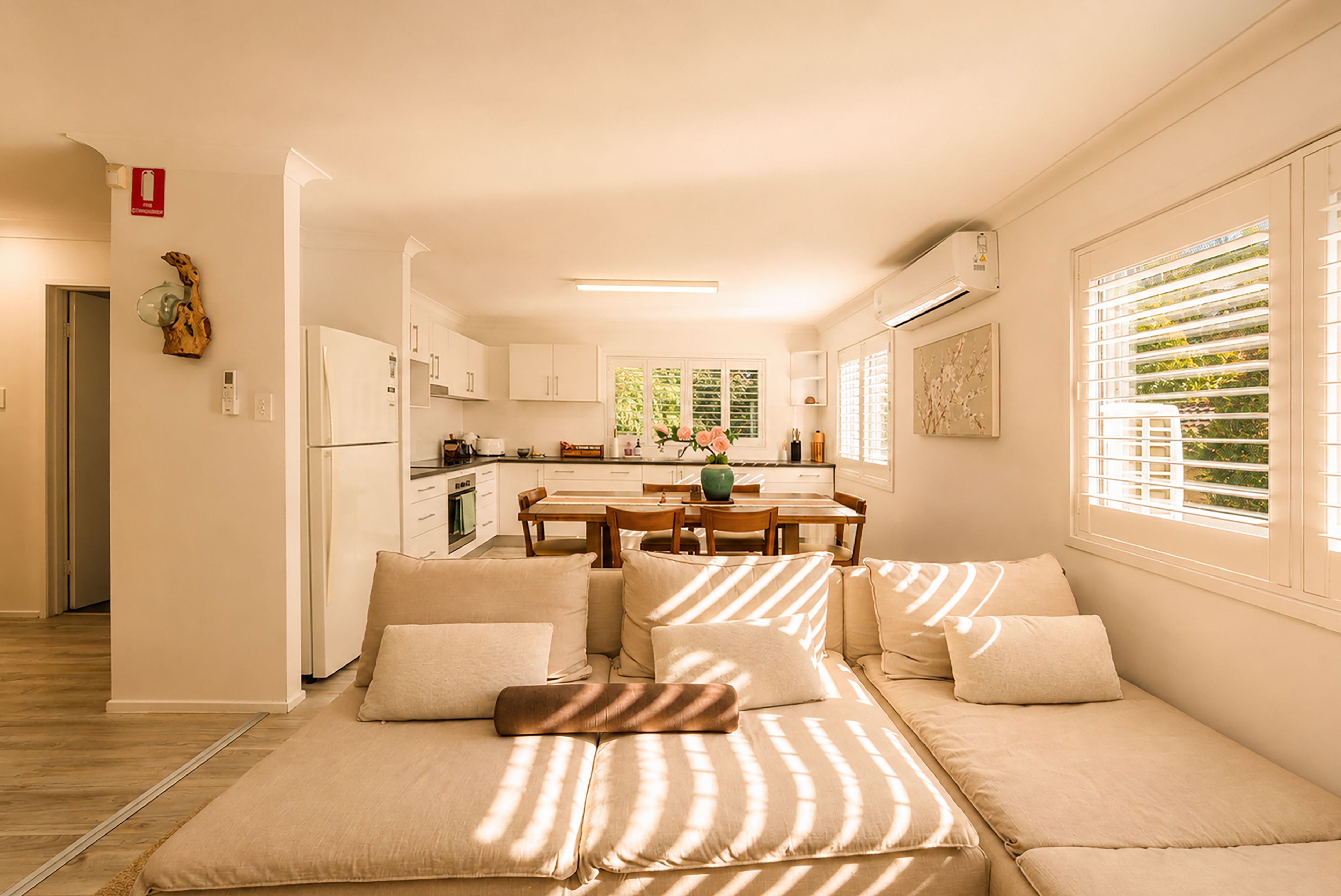 A modern living room with a sofa, a dining table, and a kitchen in the background.