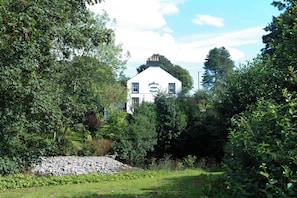 A white building with a sign reading 'Stanley Arms Hotel' surrounded by lush greenery and a stone pile. - The Stanley Arms Hotel by Guestz (Seascale)
