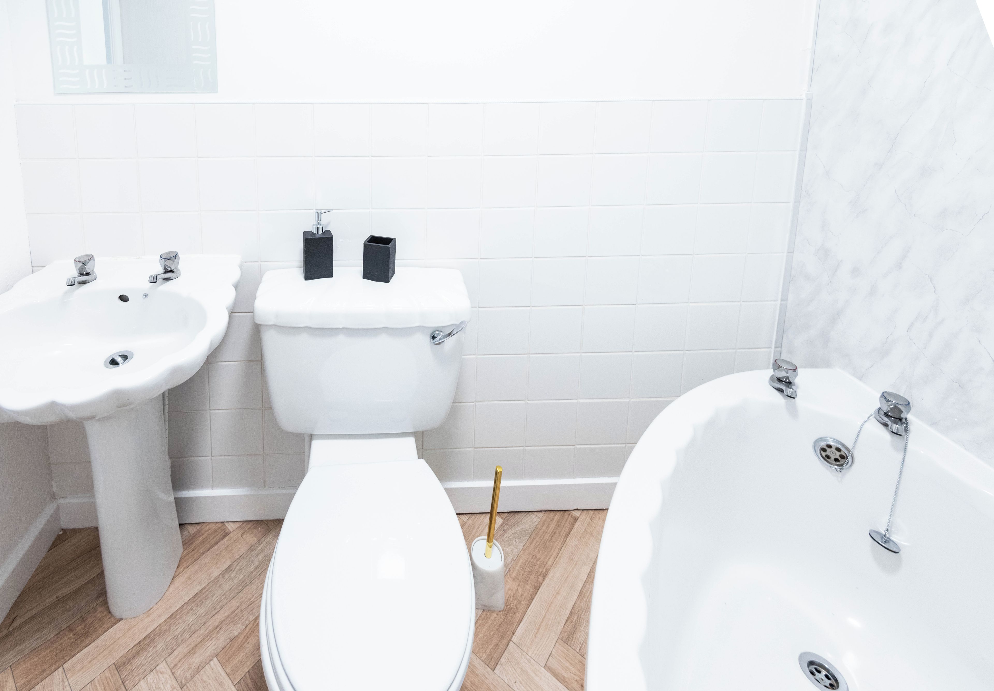 A bathroom with a toilet, two sinks, and a bathtub.