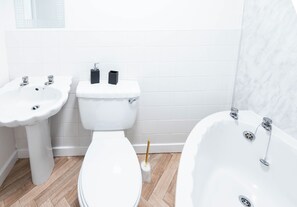 A bathroom with a toilet, two sinks, and a bathtub.