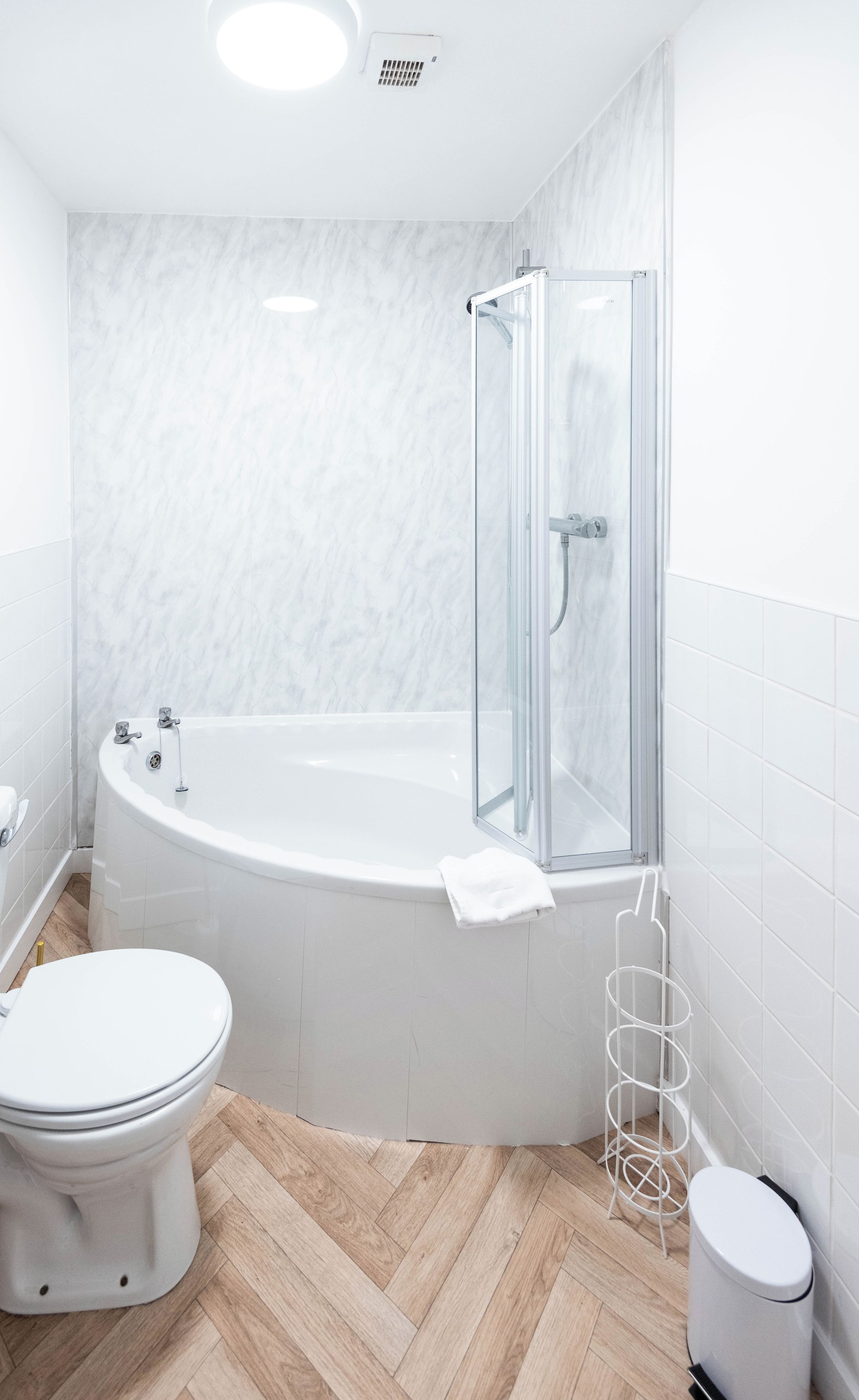 A modern bathroom with a freestanding bathtub, a toilet, and a shower enclosure.