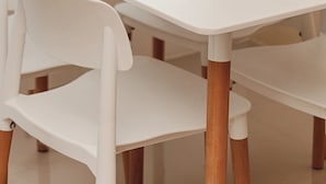 Een eettafel met witte stoelen, borden en bestek.