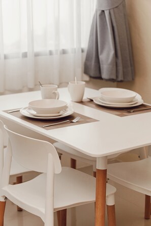 A dining table with white chairs, plates, and cutlery. - The One House (Rawai)