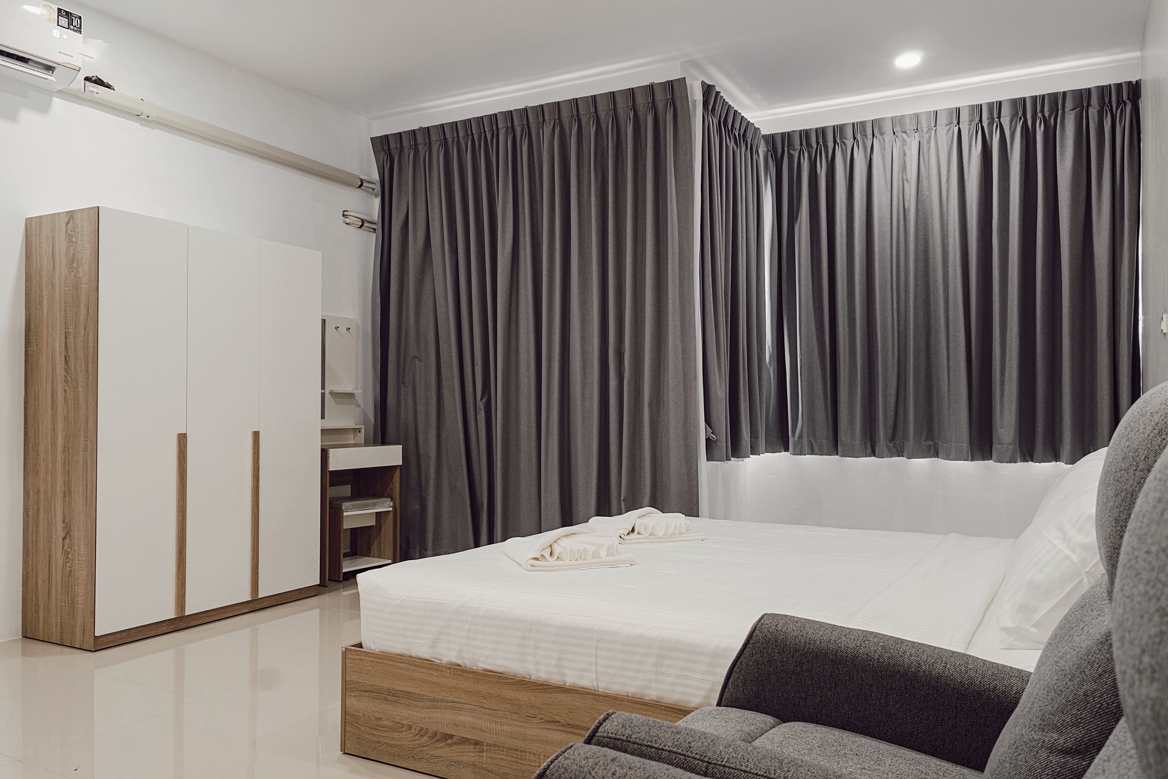A modern bedroom with a bed, a wardrobe, and a large window with curtains.