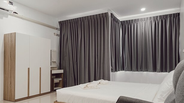 Een moderne slaapkamer met een bed, een kledingkast en een groot raam met gordijnen.