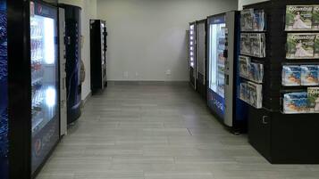 A hallway with vending machines on both sides, one vending Pepsi and the other vending magazines.