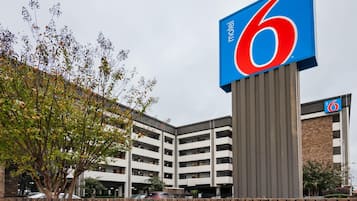 Een motel met een opvallend bord met het cijfer '6', een parkeergarage en een bakstenen muur.