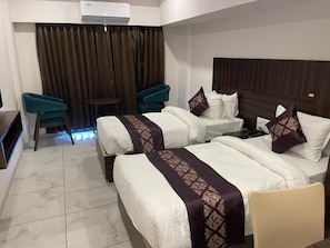 A hotel room with two beds, a small table, two chairs, and a curtain backdrop.