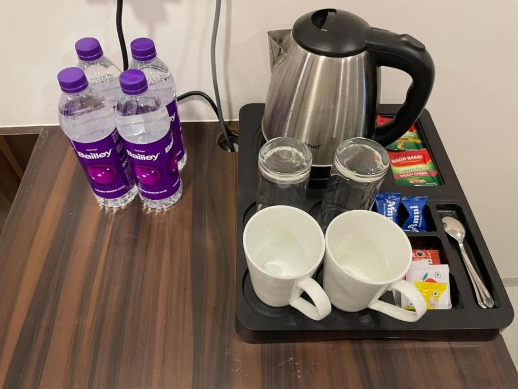 A tray with Bailey's water bottles, a kettle, two mugs, two glasses, and some food packets.