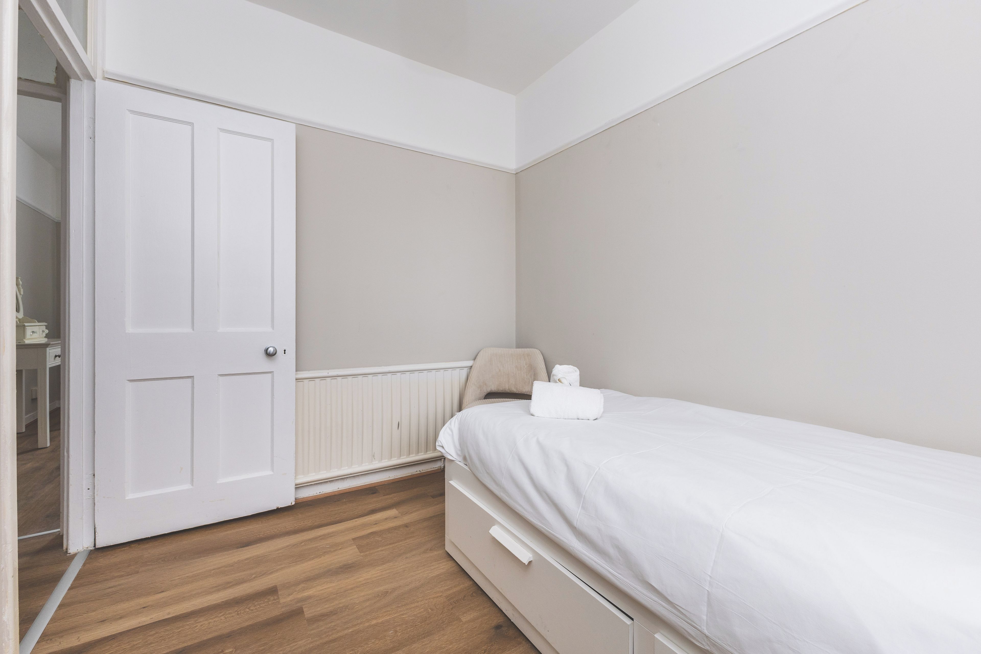 Een slaapkamer met een eenpersoonsbed, een gesloten deur en een radiator.