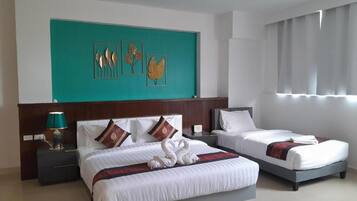 Habitación de hotel con dos camas, una pared de acento color turquesa y un ventanal con cortinas.