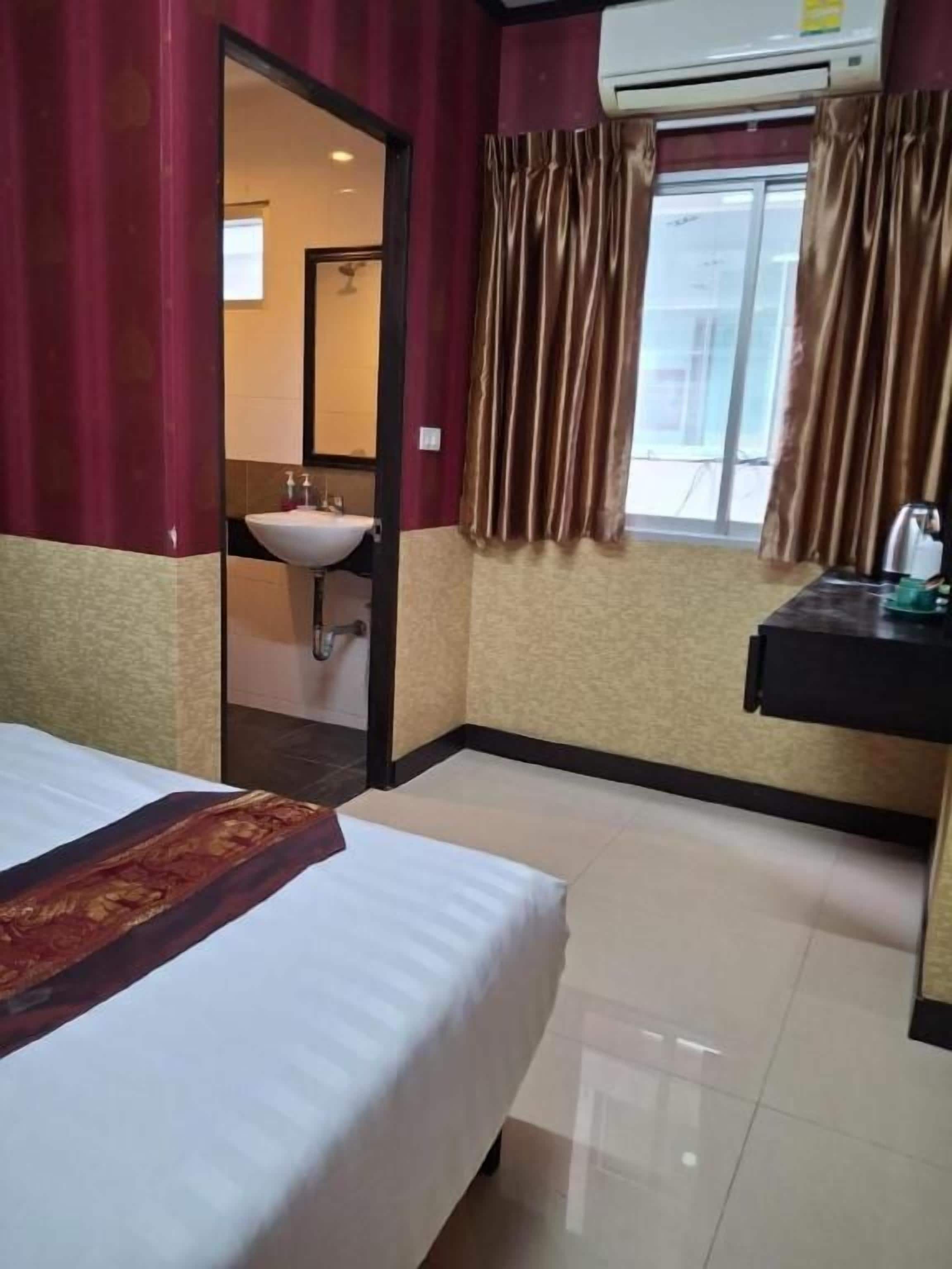 A hotel room with a bed, a sink, and a window with curtains.