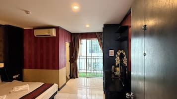 Habitación de hotel con cama, escritorio, armario y vista al exterior.