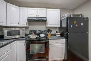 A kitchen with white cabinets, a microwave, stove, oven, and a refrigerator. - Valley Retreat Near Massanutten & Harrisonburg (Penn Laird)