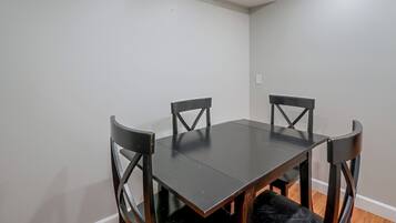 Une table à manger avec quatre chaises, un mur de couleur claire et un plancher en bois.