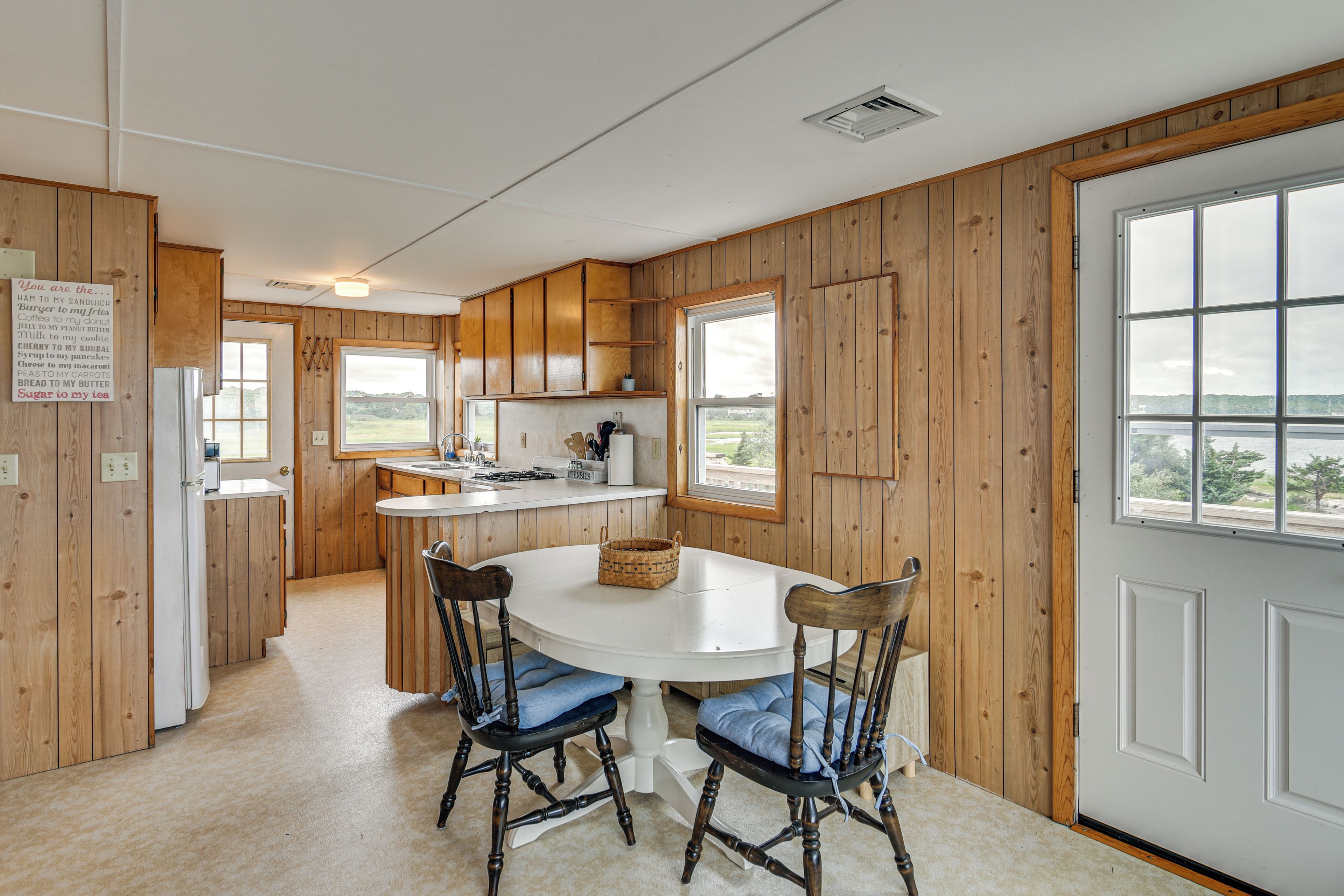Una cucina con rivestimenti in legno, un tavolo da pranzo con sedie e vista dalle finestre.