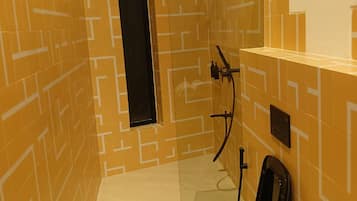 A small, narrow bathroom with a geometric patterned tile design, a black toilet, and a towel hanging on the wall.