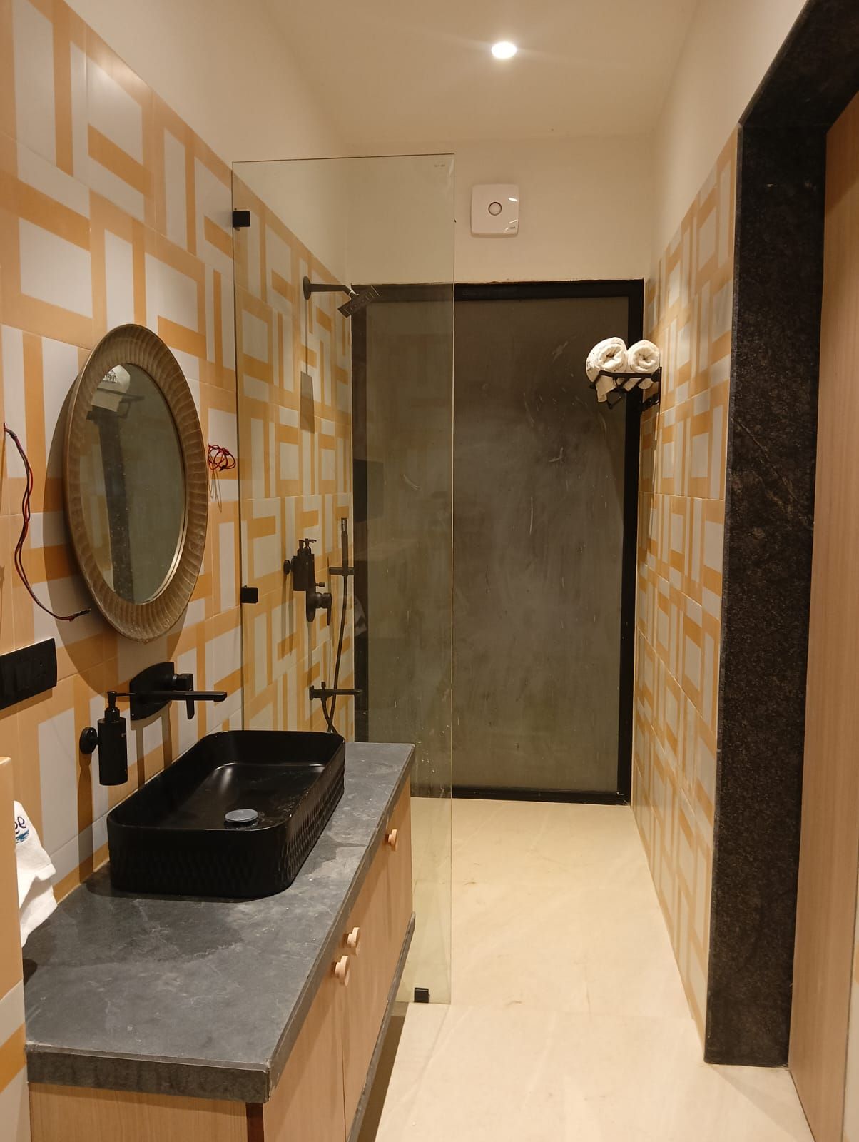 Une salle de bain moderne avec un lavabo noir, un miroir et un porte-serviettes.