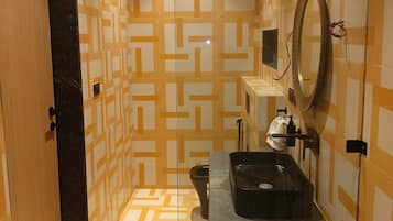 Un baño con paredes decoradas, un lavabo, un espejo y un inodoro.