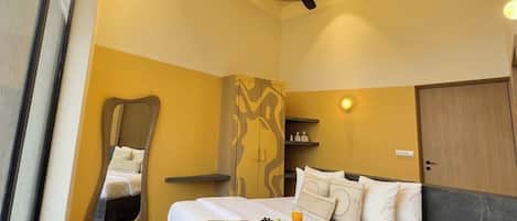 A hotel room with a bed, a unique mirror, a wardrobe, and a ceiling fan.